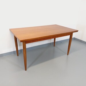 May include: A rectangular wooden dining table with a light brown finish. The table has four legs and a simple design.