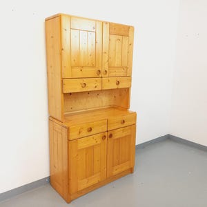May include: A wooden cabinet with two doors and two drawers. The cabinet is made of light wood and has a simple design.
