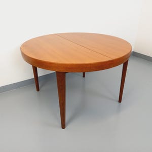 Könnte beinhalten: Ein runder Holztisch mit einer Klappplatte. Der Tisch hat eine hellbraune Farbe und vier Beine.