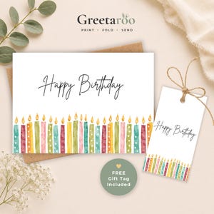 Pode incluir: Um cartão de aniversário branco e uma etiqueta de presente a condizer, ambos com uma fila de velas de aniversário em aguarela na parte inferior e o texto Happy Birthday em letra cursiva preta. A marca Greetaroo está impressa no topo.