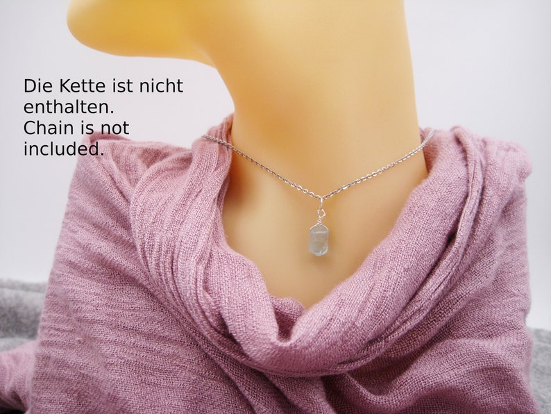 May include: A silver chain necklace with a light blue crystal pendant. The text "Die Kette ist nicht enthalten. Chain is not included." is visible in the image.