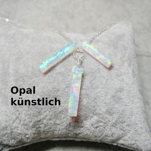 Könnte beinhalten: Eine silberne Halskette mit drei schimmernden Opal-Bar-Anhängern. Die Halskette liegt auf einem grauen Hintergrund und der Text "Opal künstlich" ist sichtbar.