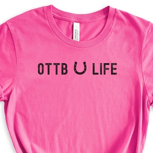 May include: Pink t-shirt with the text "OTTB U LIFE" in black.