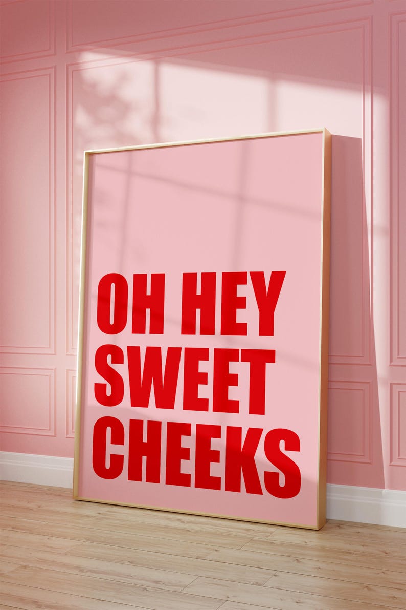 May include: A pink framed poster with the text "OH HEY SWEET CHEEKS" in red letters.