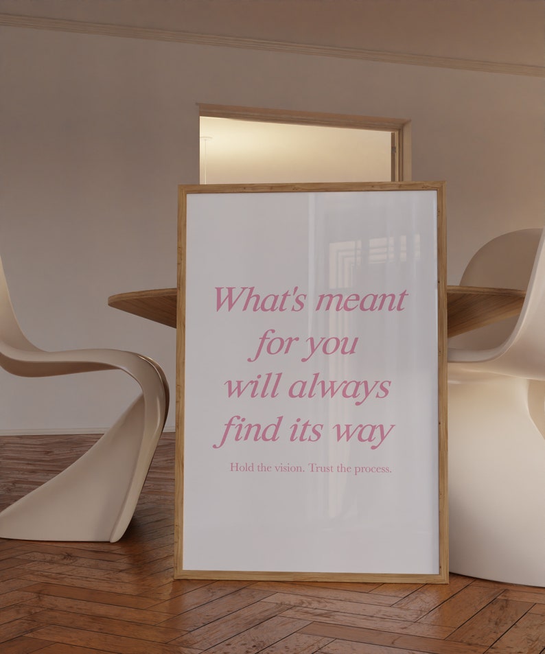 May include: A framed poster with a white background and pink text that reads 'What's meant for you will always find its way.' The text is in a cursive font. Below the text is a smaller line of text that reads 'Hold the vision. Trust the process.'
