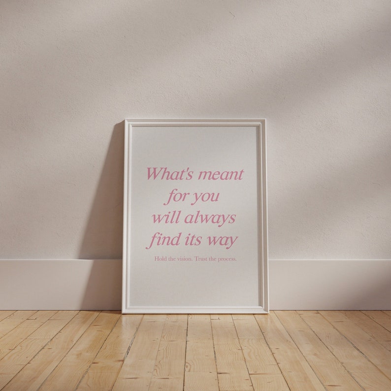May include: A white framed print with a pink quote that reads 'What's meant for you will always find its way. Hold the vision. Trust the process.'