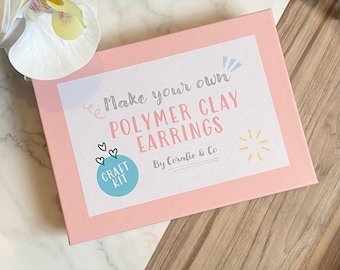 May include: Pink box with a white label that says "Make your own POLYMER CLAY EARRINGS" with a blue circle that says "CRAFT KIT" and the text "By Coralie & Co".