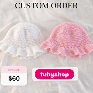 May include: Two handmade crochet bucket hats, one white and one pink, with frilled brims. The hats are displayed on a white surface. The text "CUSTOM ORDER" is at the top of the image.
