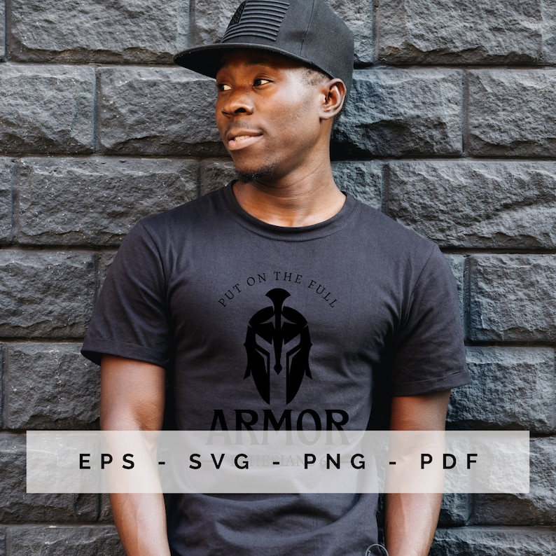 May include: Black t-shirt featuring a Spartan helmet design and the text "PUT ON THE FULL ARMOR". The shirt also displays the file types: EPS, SVG, PNG, and PDF. The person in the image is wearing a black cap.