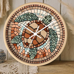 May include: Round wall clock with a mosaic turtle design. The clock face features a turtle in shades of brown, green, and blue, surrounded by a mosaic border. The clock has a light wood frame and white clock hands.
