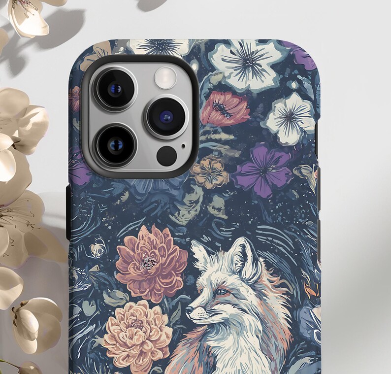May include: A phone case featuring a detailed illustration of a fox with a floral background. The case has a dark blue base with flowers in shades of pink, purple, and white. The fox is depicted in shades of orange, white, and brown.