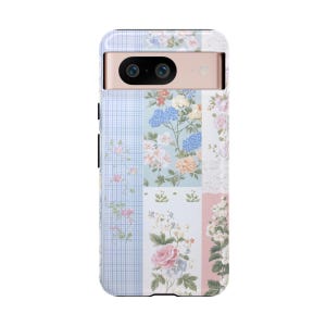 May include: A phone case with a floral patchwork design in shades of pink, blue, and white. The case has a raised camera bump with two lenses.
