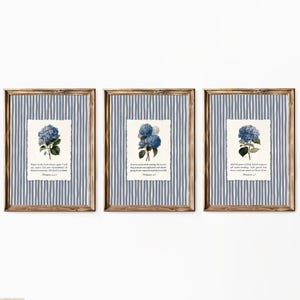 May include: Three framed prints featuring blue hydrangea illustrations on a white background with text. The frames have a wood-like appearance and are set against a blue and white striped background. The prints are displayed on a white wall.