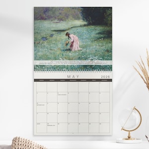 May include: A 2026 wall calendar featuring a pastoral painting of a woman in a field of flowers. The calendar is open to May, with a grid of dates and the text "For I know the plans I have for you..." at the top.