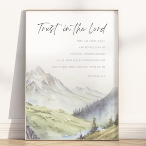 May include: Framed art print featuring a watercolor landscape of mountains and a river. The text "Trust in the Lord" is at the top, with a Bible verse below. The artwork has a soft, muted color palette.
