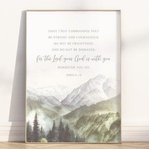 May include: Framed art print with a watercolour landscape of mountains and trees in green and grey tones. The print includes the text "Have I not commanded you? Be strong and courageous..." from Joshua 1:9.