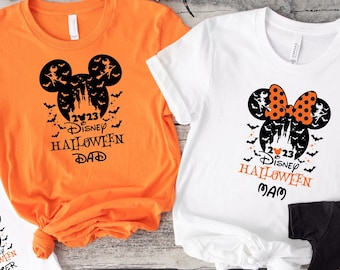 May include: Four t-shirts with a Disney Halloween theme. The shirts are orange, white, and black. The shirts feature Mickey Mouse and Minnie Mouse ears with bats and the text "I 23 Disney Halloween" with "Dad", "Mom", "Sister", and "Brother" on each shirt.