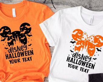 May include: Three t-shirts featuring a black and white graphic of Mickey Mouse ears with bats and a castle. The text "disney HALLOWEEN YOUR TEXT" is on each shirt. The shirts are orange, white, and black.