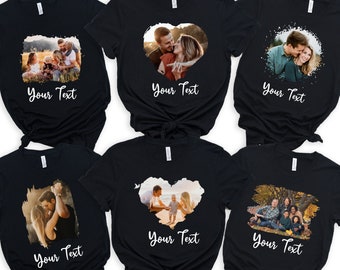 Puede incluir: Seis camisetas negras con diferentes fotos impresas en ellas. Cada camiseta tiene un diseño en forma de corazón alrededor de la foto y el texto "Your Text" debajo de la foto.