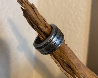 Könnte beinhalten: Ein silberner Ring mit einem floralen Design. Der Ring ist aus einer wiederverwendeten Münze gefertigt und zeigt eine Rose und Blätter.
