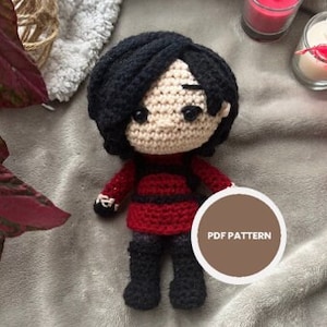 Könnte beinhalten: Gehäkelte Amigurumi-Puppe mit schwarzen Haaren, roten und schwarzen Kleidern und einem braunen Kreis mit dem Text "PDF PATTERN".