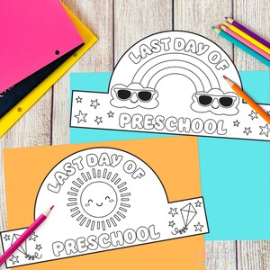 May include: Two printable preschool graduation crowns. One crown features a rainbow with sunglasses and the text "LAST DAY OF PRESCHOOL." The other crown has a smiling sun and the same text. Colored pencils and paper are in the background.