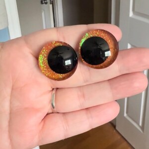 May include: Two round, orange and black, glitter-covered, plastic eyes for crafts.