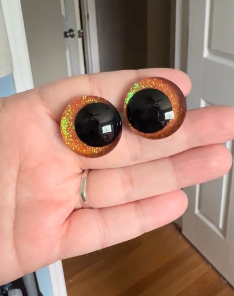 May include: Two round, orange and black, glitter-covered, plastic eyes for crafts.