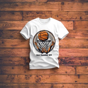 以下が含まれることがあります： バスケットボールがフープを通過するグラフィックが描かれた白いTシャツ。グラフィックは黒とオレンジで、"Since December 1891"というテキストが含まれています。