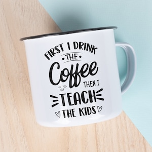 May include: White enamel mug with a black handle and black text that reads "First I drink the coffee then I teach the kids".