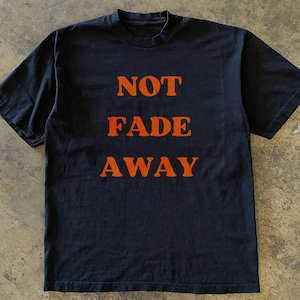 May include: Black t-shirt with the words "NOT FADE AWAY" printed in orange.