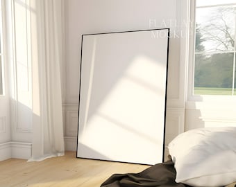 May include: A large, black framed poster mockup in a white room with a window and a white bed with a brown blanket and white pillow.