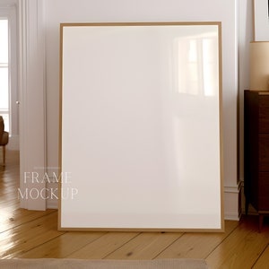 Könnte beinhalten: Ein großer, leerer Holzrahmen mit einer hellbraunen Oberfläche. Der Rahmen steht auf einem Holzboden in einem Raum mit weißen Wänden.