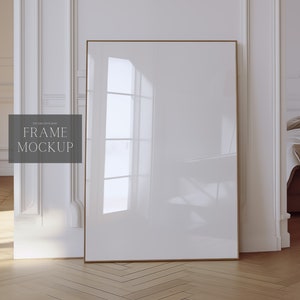 Könnte beinhalten: Ein goldener Rahmen-Mockup in einem weißen Raum mit einem Bett im Hintergrund. Der Rahmen ist leer und bereit für Ihr Design.