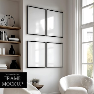 May include: Four black picture frames with white mounts are hanging on a white wall. The frames are arranged in a square shape. The wall is in a room with a white chair and a bookshelf with books and decorative objects.