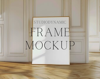 May include: A gold frame mockup in a white room with wood floors. The frame is empty and has a shadow cast on it. The text "Studiodynamic Frame Mockup" is printed on the frame.
