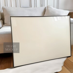 May include: A black frame mockup with a white background. The frame is sitting on a white rug in front of a white couch.
