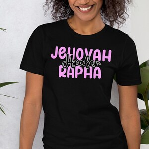 May include: Black t-shirt with the text "Jehovah Healer Rapha" in pink lettering.