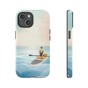May include: A phone case featuring an illustration of a person paddleboarding on a calm ocean. The artwork depicts a person in a black swimsuit sitting on a paddleboard with a paddle. The background shows a watercolor-style sky and ocean.
