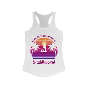 May include: White racerback tank top with a sunset graphic. The graphic features palm trees, a paddleboarder, and the text "Life is Better on a Paddleboard" in purple and white.