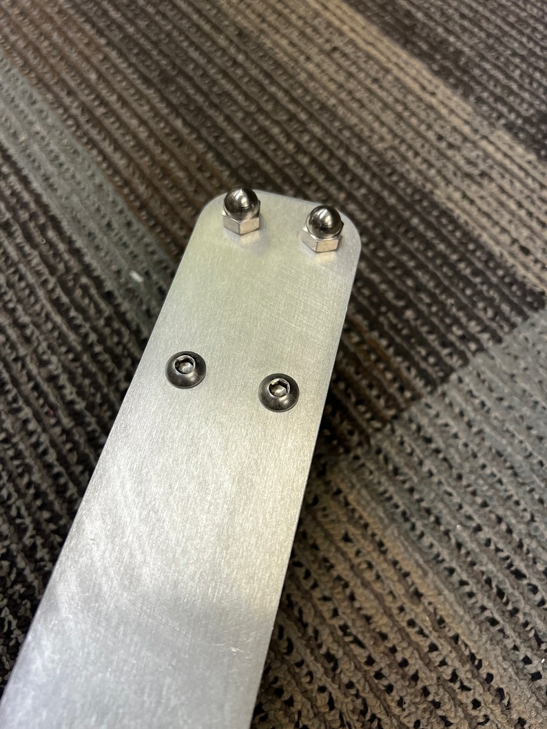 May include: A silver metal bar with four silver metal screws. The screws have round heads.
