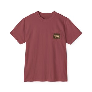 May include: A maroon t-shirt with a pocket on the left chest. The pocket features a graphic of a mountain range and the text "MILES DEEP" and "Cades Cove". The shirt has short sleeves and a crew neck.
