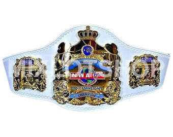 May include: A white wrestling championship belt with gold accents. The belt features the text "WOMEN'S NWA BANTAMWEIGHT CHAMPION" and a central emblem with a crown and globe design. The belt is made of white leather.
