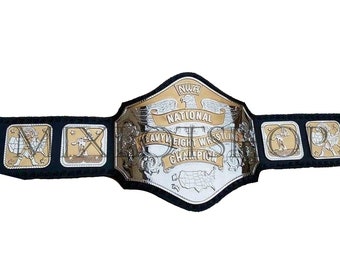May include: A wrestling championship belt with a silver and gold design. The belt features the text "NWA National Heavyweight Wrestling Champion" and images of wrestlers. The belt is black with silver and gold accents.