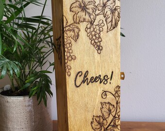 May include: Wooden wine box with a vine and grapes design, engraved with the word "Cheers!"
