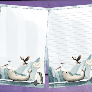 May include: Open notebook with illustrated arctic scene. Features a seal, penguins, puffins, and seagulls on a backdrop of icebergs and a light blue sky. One page is lined, the other is blank.