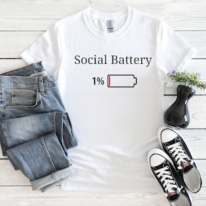 May include: White t-shirt with the text "Social Battery 1%" and a low battery icon.
