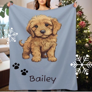 Op de afbeelding: Een zachte blauwe fleece deken met een cartoonillustratie van een golden doodle puppy. De puppy zit met zijn pootjes op de grond en heeft een schattige uitdrukking op zijn gezicht. De deken heeft de naam "Bailey" in het zwart onderaan gedrukt.