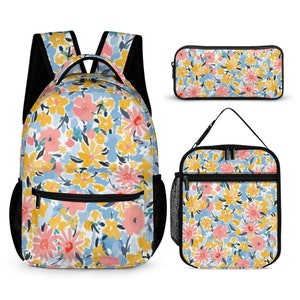 May include: A three-piece floral print school set includes a backpack, lunch bag, and pencil case. The set features a white background with a colourful floral pattern in shades of pink, yellow, and blue.