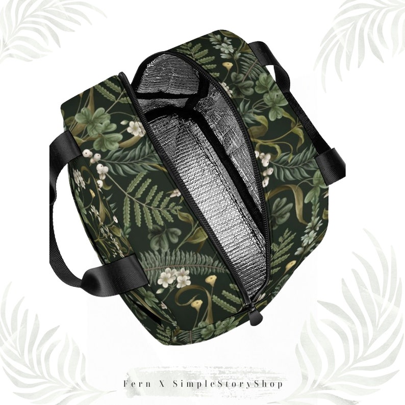May include: A black insulated tote bag with a botanical pattern of green leaves, white flowers, and berries. The bag has black handles and a silver insulated interior. The zipper is black. The text "Fern X SimpleStoryShop" is at the bottom.